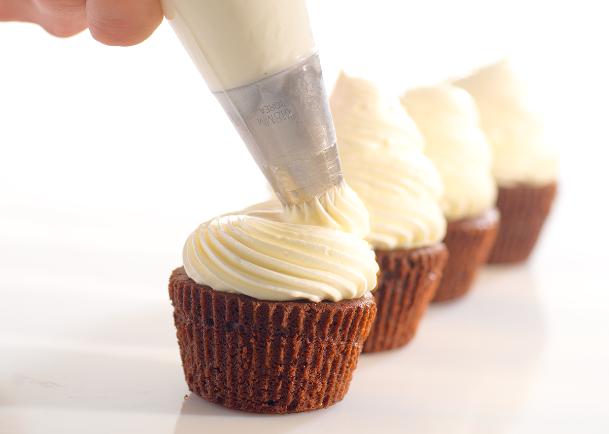 Photo d’un artisan boulanger-pâtissier qui dresse à la poche une garniture réalisée avec Aério pour la réalisation d’un cupcake.