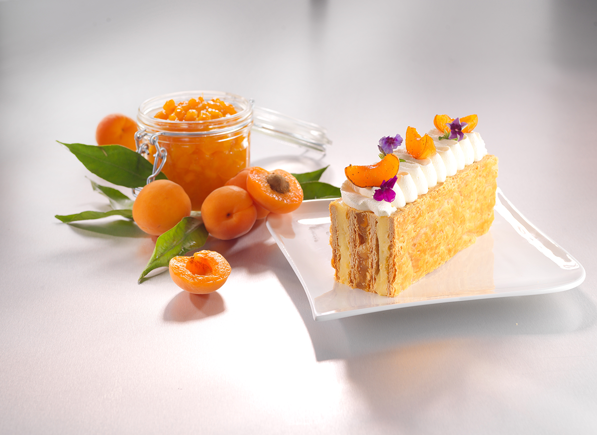 Photo d’un millefeuille goût abricot, monté à l’envers, qui comprend un fourrage à l’abricot avec des morceaux de fruits.