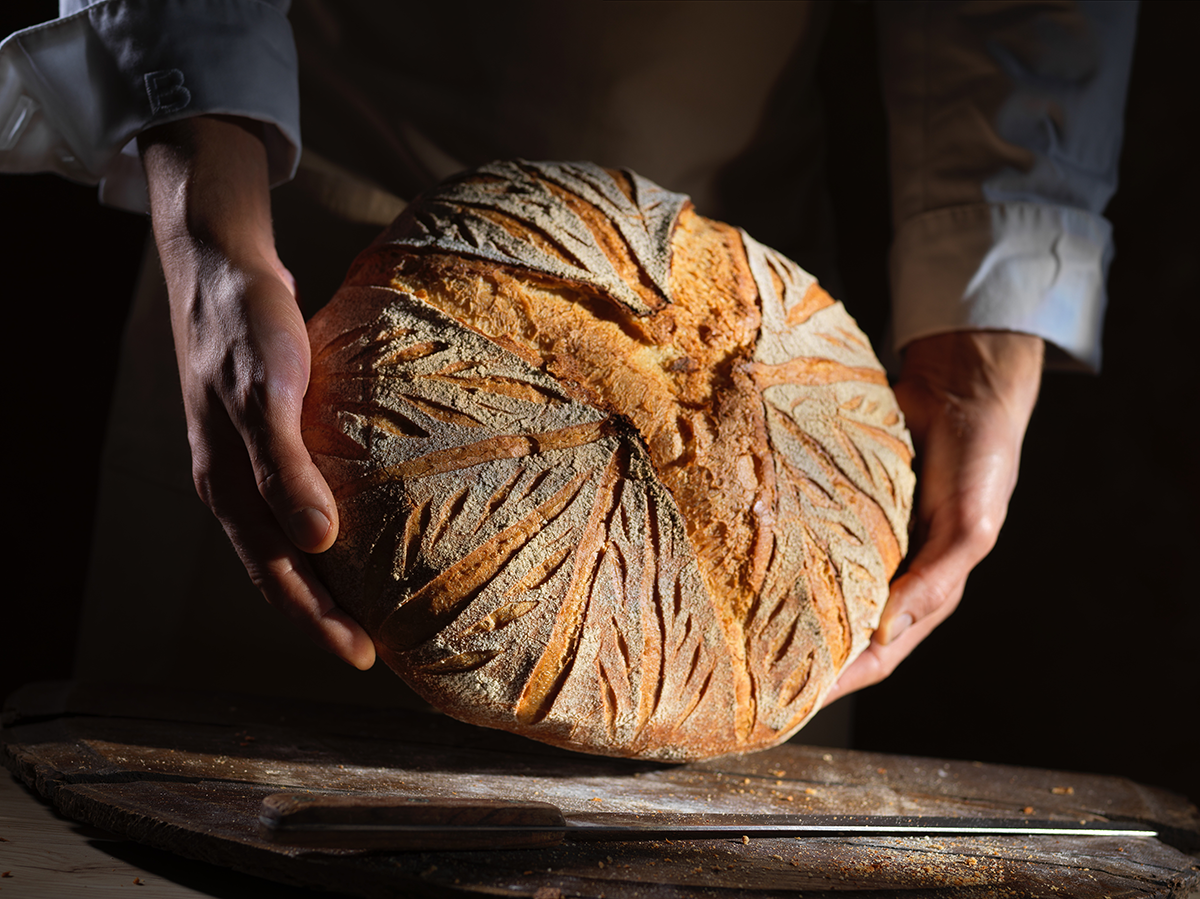 Photo d’un pain de campagne dans les mains d’un boulanger, issu du savoir-faire artisanal.