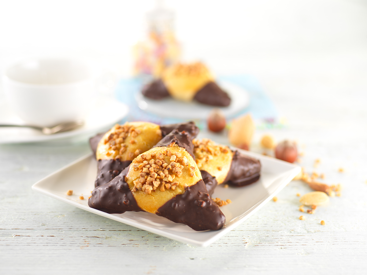 Photo d’un sablé aux amandes en forme triangulaire, composé d’une pâte à foncer sucrée, d’un fourrage amande et d’un glaçage chocolat noir.
