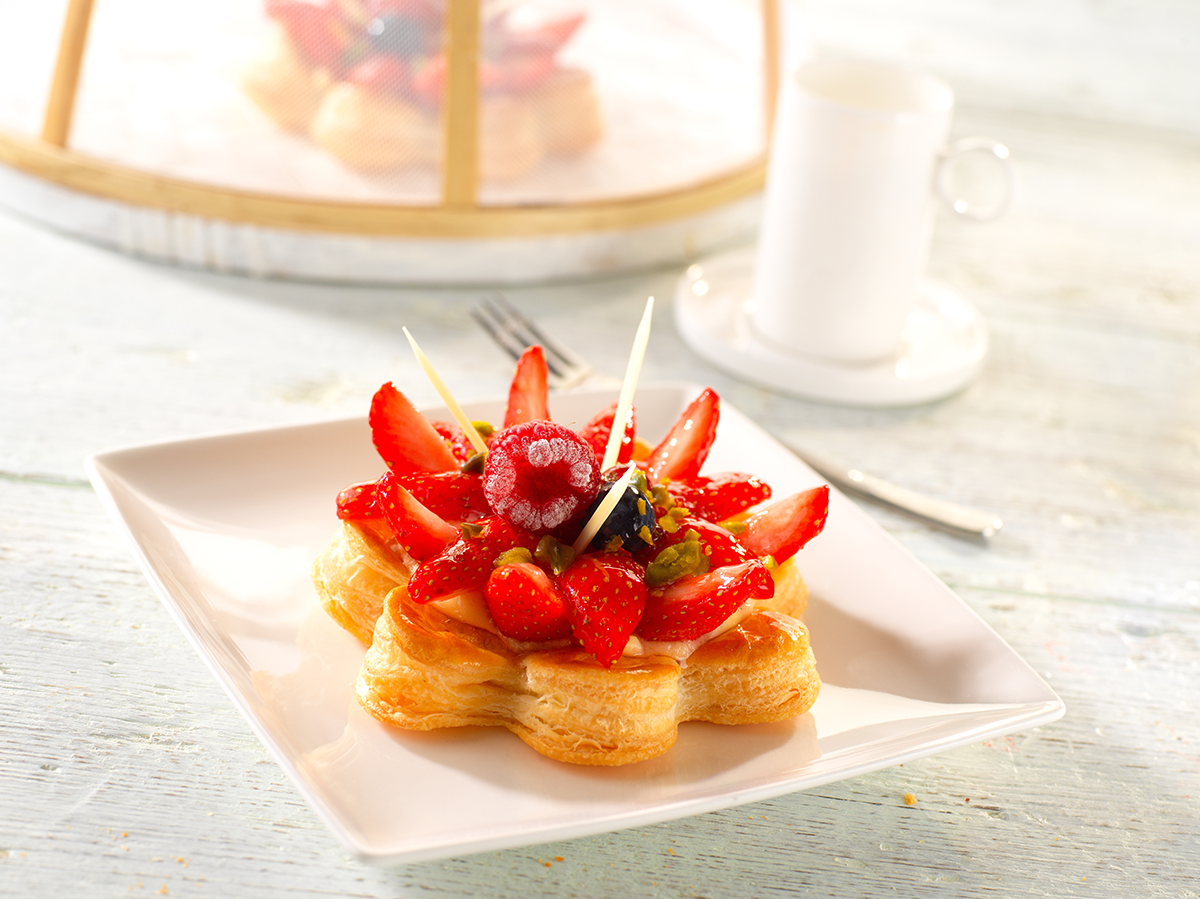 Photo d’une tartelette avec une pâte feuilletée en forme de fleur et d’un panier garni de fruits rouges pour une légèreté et une fraîcheur en bouche.