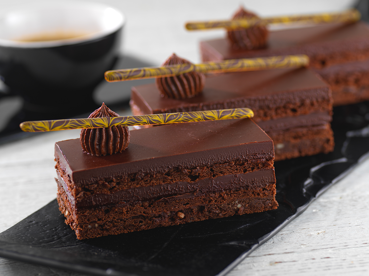 Photo d’entremets finger réalisés en cadre avec des couches successives et alternées de biscuit chocolat et de garniture cacao.