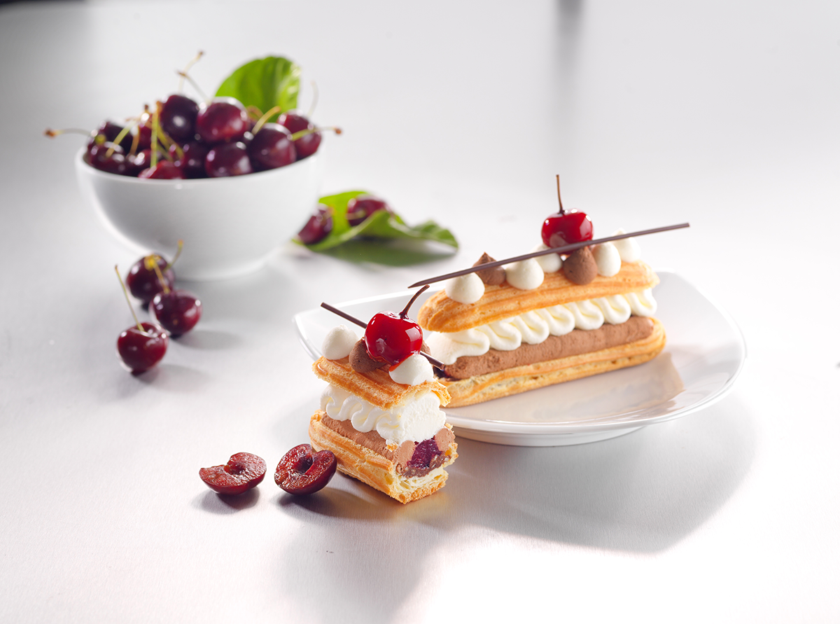 Photo d’un éclair revisité « forêt noire », une fusion entre deux desserts intemporels de la pâtisserie française, pour les addicts de cerises.