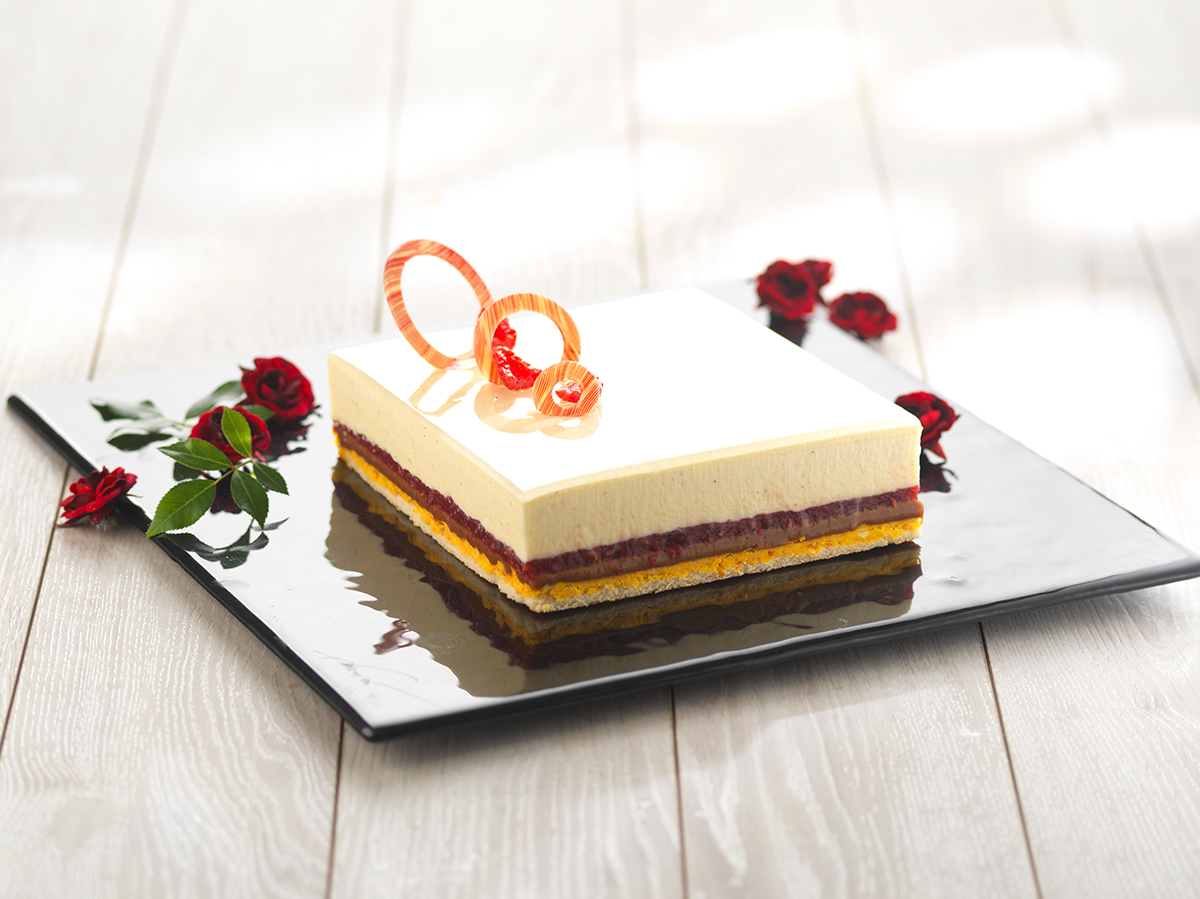 Photo d’un entremets carré pour 6 personnes, avec une mousse au caramel, un croquant à la passion et un fourrage à la framboise pour une note acidulée.
