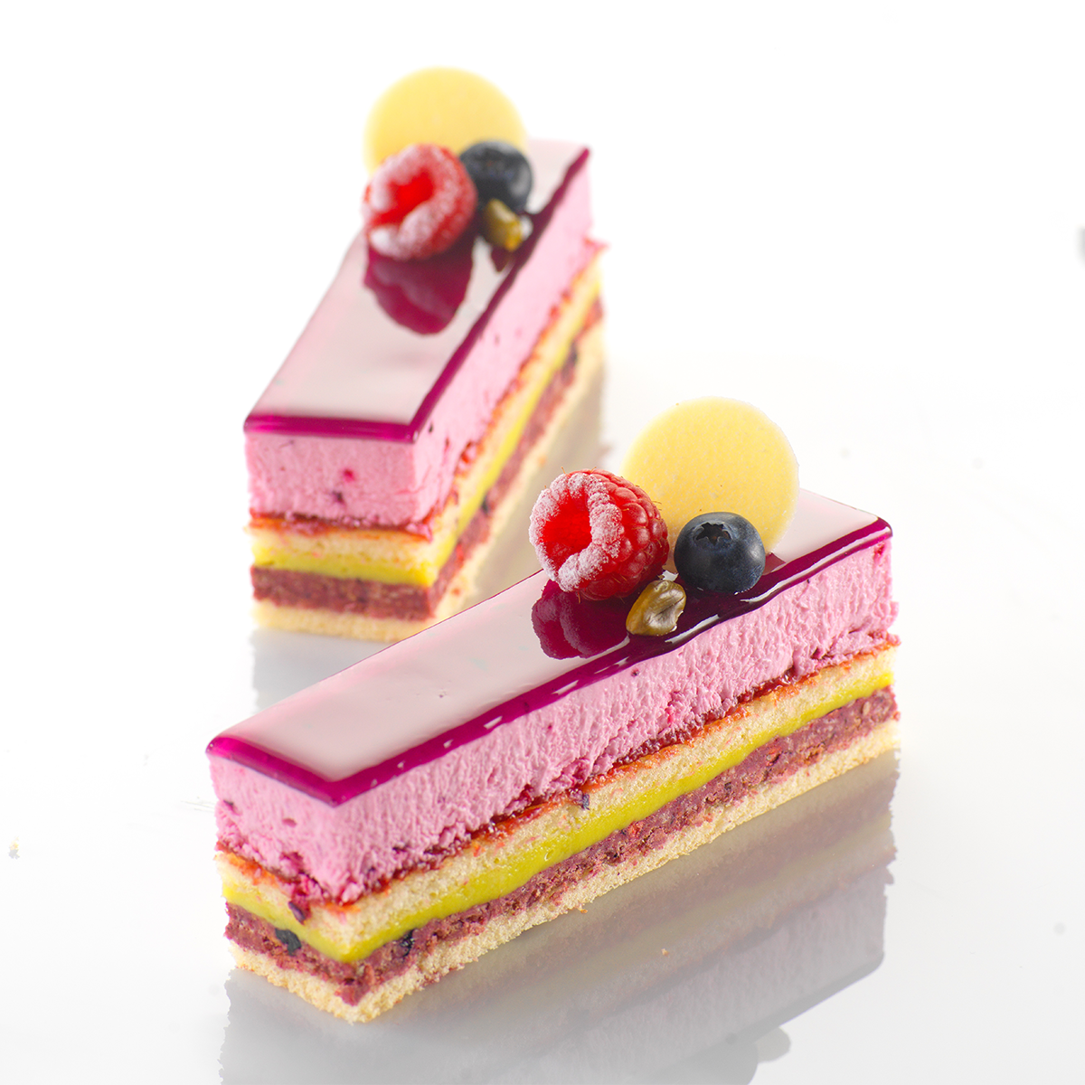 Photo d’un entremets composé d’un biscuit surmonté d’un croustillant au citron et d’une mousse à la framboise réalisée avec le fourrage aux fruits Fruffi Framboise et une crème montée.