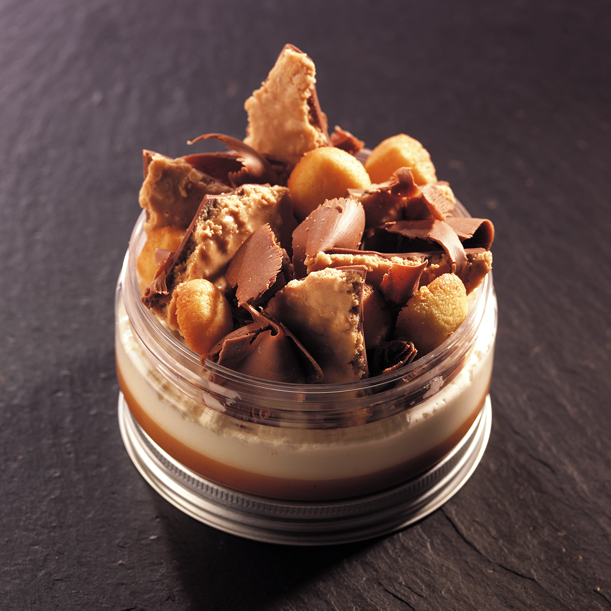 Image d’une verrine avec une mousse au chocolat blanc et d’un crémeux au  caramel avec des inclusions croquantes de caramel à la fleur de sel, des  biscuits sablés et du chocolat au lait